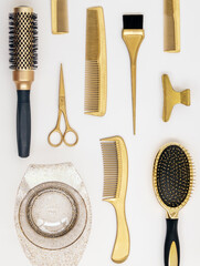 Vertical background with golden hairdresser tools. Hair salon accessories, comb, scissors on white.