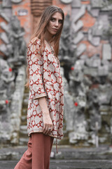a model girl in a fashionable suit posing against the background of a historical monument. Full-length studio fashion portrait