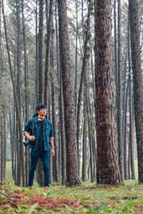 Fototapeta premium Traveler woman take a photograph in nature Pine Park. Tourist with camera travel photo of photographer Making pictures Traveling Trip Sightseeing Tourism concept.