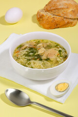 Homemade chicken noodles in a white deep plate on a white napkin and yellow background.