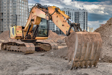 Crawler Excavator Machine Unloading Sand or Soil at Construction Area Background. Close-up of an excavator bucket with an extended boom. Rental of construction equipment. earthworks contractor.