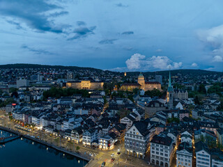 Aerial view over the old town of Zürich with Limmat River and city lights on a spring evening with dramatic sky. Photo taken May 6th, 2023, Zurich, Switzerland.