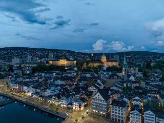 Aerial view over the old town of Zürich with Limmat River and city lights on a spring evening with...