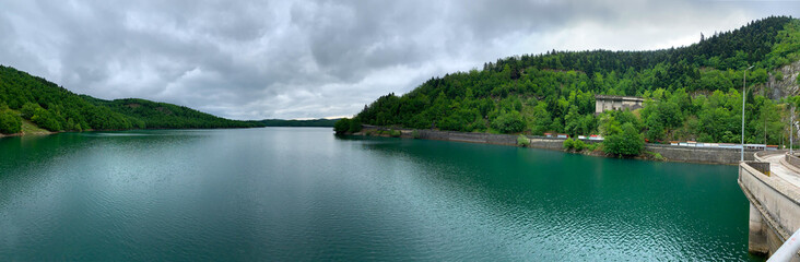 Lake Plastiras beautiful nature, panoramic view from the Dam to the green forested shores and the emerald water under darkening clouds. Man made Tavropos lake, “Little Switzerland”, Karditsa, Greece.
