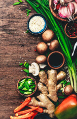 Asian cuisine ingredients with vegetables, food background. Ginger, lime, chili pepper, garlic, soy sauce, mushrooms, paprika, green onion on wooden kitchen table. Top view