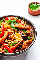 Stir fry noodles with chicken, red paprika, mushrooms, chives and sesame seeds in bowl. Asian cuisine dish. White table background, top view
