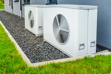 Two air source heat pumps installed outside of new and modern city house