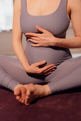 Fototapeta na wymiar Young pregnant woman doing yoga exercises and meditating at studio. Health care, mindfulness and wellness concept.