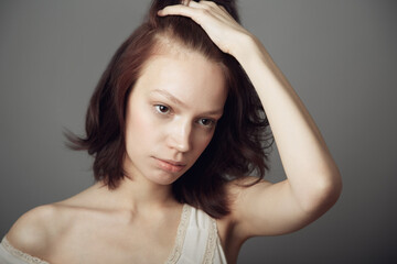 Sad woman, stress and anxiety with hand on hair in mental health problem isolated on a grey studio background. Anxious, stressed or depressed young female model holding head in thought on backdrop