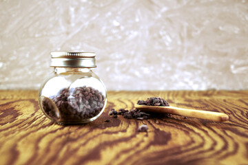 Black salt Kala namak in a glass salt shaker and on a wooden spoon on the table