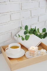Fototapeta na wymiar Cup of tea, book and white candles on wooden tray