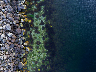 Birds eye shot revealing a fade from rocky textures to a dark sea