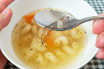 Person found long hair in his plate of soup and isn't satisfied with the food. Situation causing nausea. Failure to follow hygienic cooking practices, bad customer service, no chefs hat.