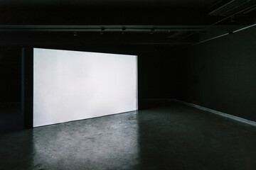 Empty room with blank mockup movie screen monitor standing in dark theater on black wall...