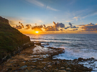 Obraz premium Sunrise and clouds over the ocean and rock platform