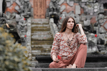 Fototapeta premium a model girl meditates near a shrine, poses for a temple in a tropical forest, long hair 4k