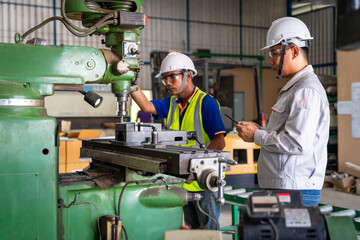 Asian engineer and worker operating lathe grinding machine - metalworking industry concept. Mechanical Engineering control lathe machine in factory.