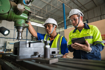 Asian engineers working with worker wearing safety goggles working at lathe. Safety first concept. © tong2530