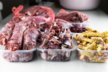 A man prepares various raw meats, bones and offal for freezing. BARF Biologically Appropriate Raw Food for Dogs and Cats. Animal food packaging.