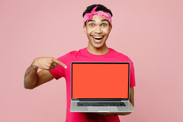 Young IT man of African American ethnicity wear headscarf t-shirt casual clothes work hold use point on blank screen workspace area laptop pc computer isolated on pastel plain pink color background.