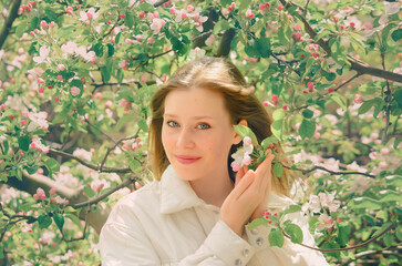 Portrait of a beautiful young girl in an Apple blossom garden