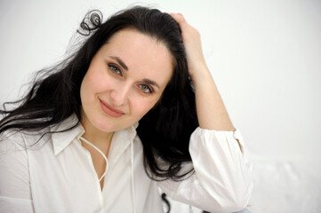 Portrait of a young successful woman with dark hair. The woman straightens her hair with her hands. High quality photo