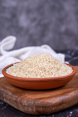 Sesame seeds on dark background. Organic White Sesame seeds (Sesamum indicum) in Earthen bowl. Close up