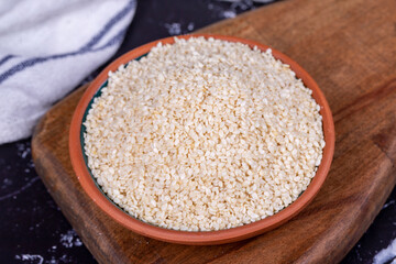 Sesame seeds on dark background. Organic White Sesame seeds (Sesamum indicum) in Earthen bowl. Close up
