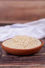 Sesame seeds on wooden background. Organic White Sesame seeds (Sesamum indicum) in Earthen bowl. Close up