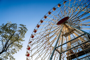 Ferris wheel in the amusement park against the background of the summer sky