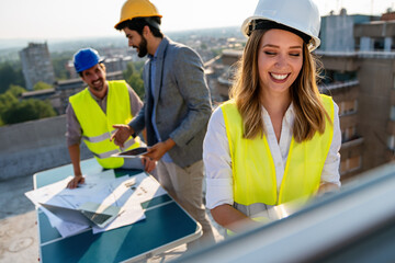 Diverse team of specialists with computer on construction site. Building project with engineers