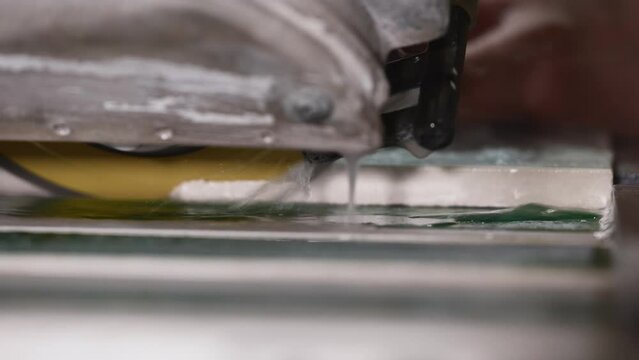 The process washed down the seam of porcelain tiles at forty-five degrees. A hydraulic cutter is used to finish the edges.