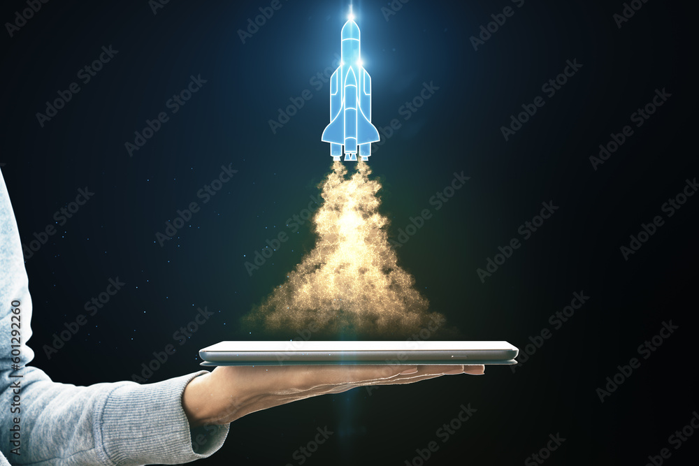 Poster Beginning of new business project and technological startup concept with hologram of starting rocket with a flame in a neon style over digital tablet on hand on dark background