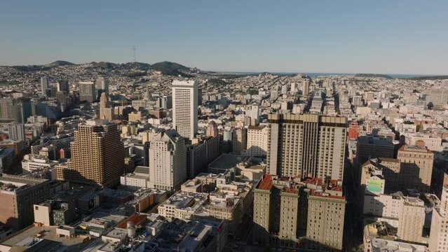 Forwards fly above buildings in urban borough at golden hour. Famous Westin St Francis hotel lit by morning sun. San Francisco, California, USA