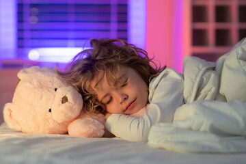 Kid enjoying sweet dreams. Kid take nap. Child sleeping with a toy teddy bear in bed, comfortable...