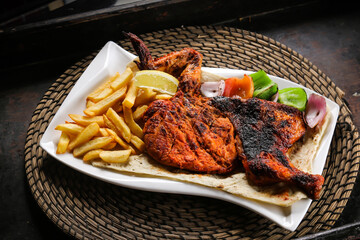 Full Chicken Grill with fries and salad served in dish isolated on red mat top view on table arabic food