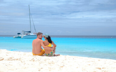 a couple of men and women on a boat trip to Small Curacao Island with a white beach and turqouse colored ocean