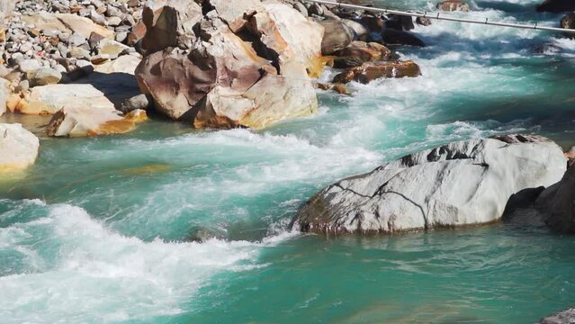 Slow motion shot of the Paravti River flowing in between mountains at Kasol in Himachal Pradesh, India. View of the Parvati river during the winter. Natural river in the mountains background.