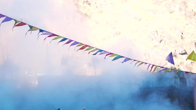 Slow motion shot of the prayer flags in front of the water vapor emitted by natural hot water springs at Manikaran in Himachal Pradesh, India. Prayer flags in front of the mist in India