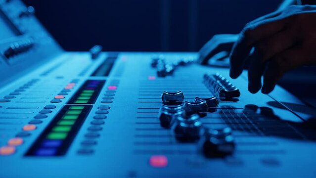 A man's hands move the sticks of a professional sound controller