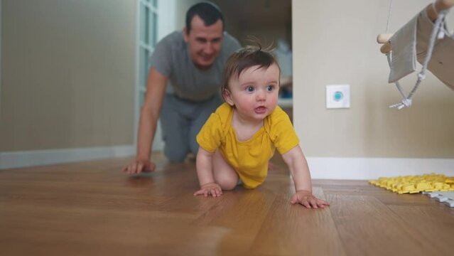 baby crawl first steps. dad play a baby toddler take crawl at home. happy family kid dream concept. baby daughter learning to take first steps indoors. dad teaches walk toddler indoors lifestyle