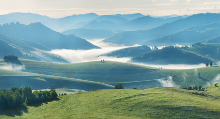 Mountains and hills in morning light, fog in the valley