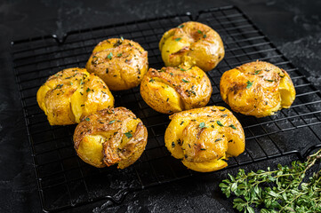 Crushed, smashed potatoes baked with rosemary and thyme. Black background. Top view