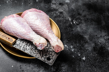 Fresh turkey legs Drumsticks, raw Poultry meat with butcher cleaver. Black background. Top view....