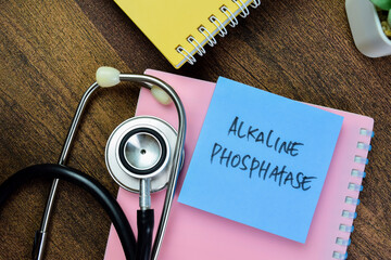 Concept of Alkaline Phosphatase write on sticky notes with stethoscope isolated on Wooden Table.