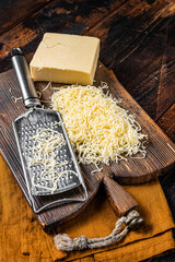 Piece of semi hard cheese and grated cheese with grater. Wooden background. Top view