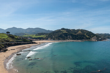 A praia em Deba na costa Basca em Espanha num bonito dia com o céu azul e com algumas casas e montanhas ao fundo