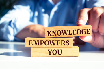 Close up on businessman holding a wooden block with "Knowledge Empowers You" message