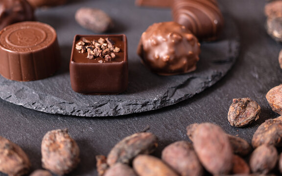 Macro shot of a tasty looking chocolate praline on a slate plate with cocoa beans around