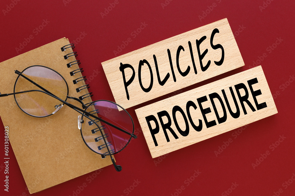 Aufkleber policies and procedure text on two wooden blocks on a red background
